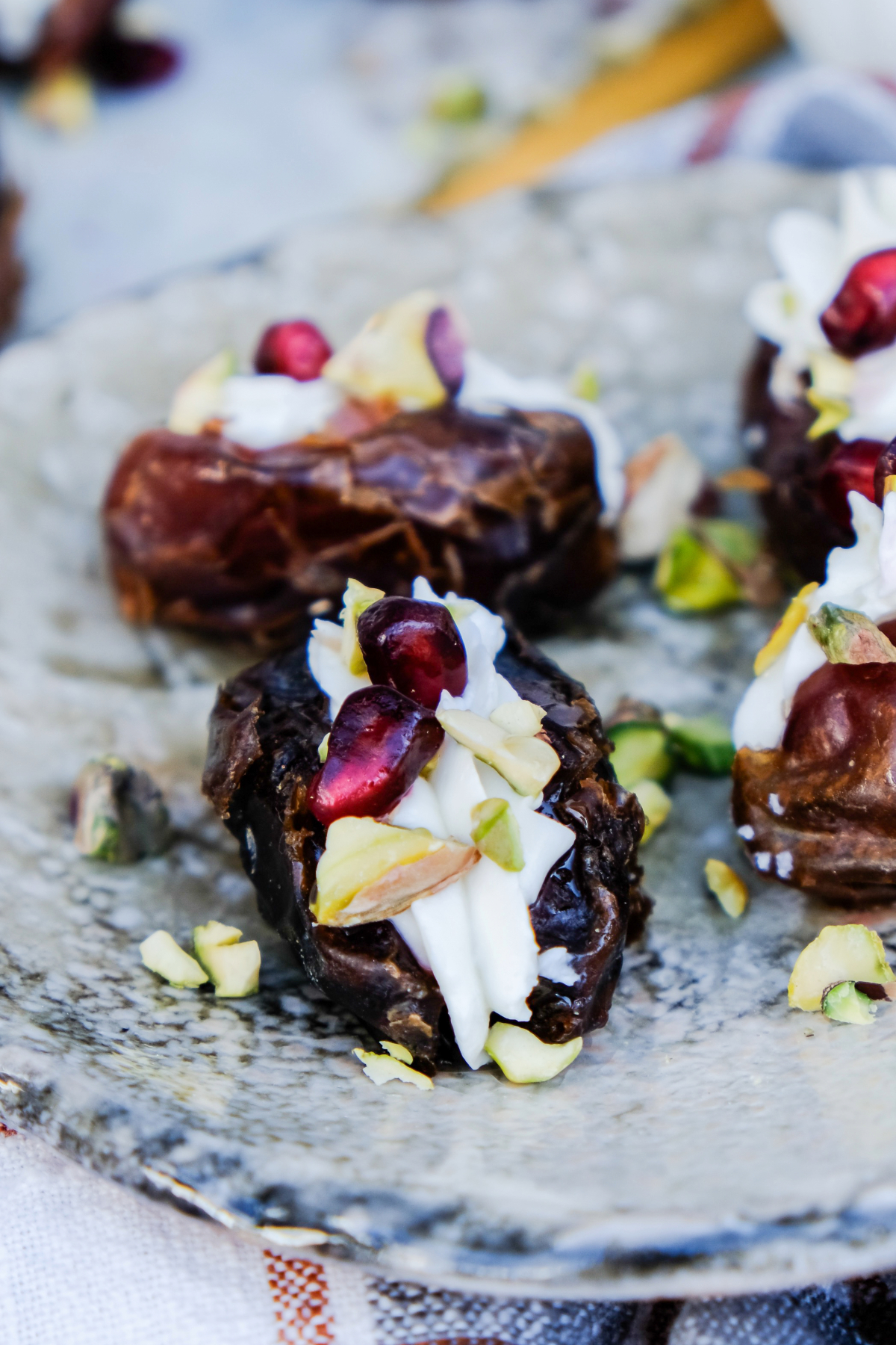 Goat cheese stuffed dates on a serving dish topped with nuts ready to eat.