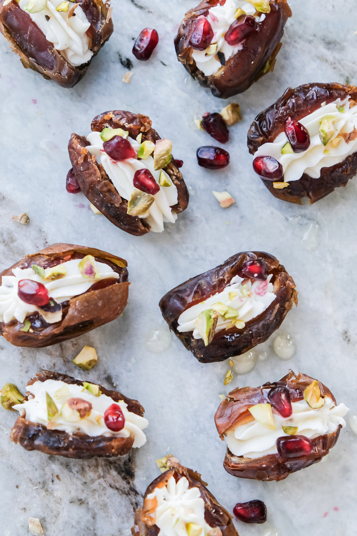 Top view of goat cheese stuffed dates topped with pistachio nuts and pomegranate seeds.
