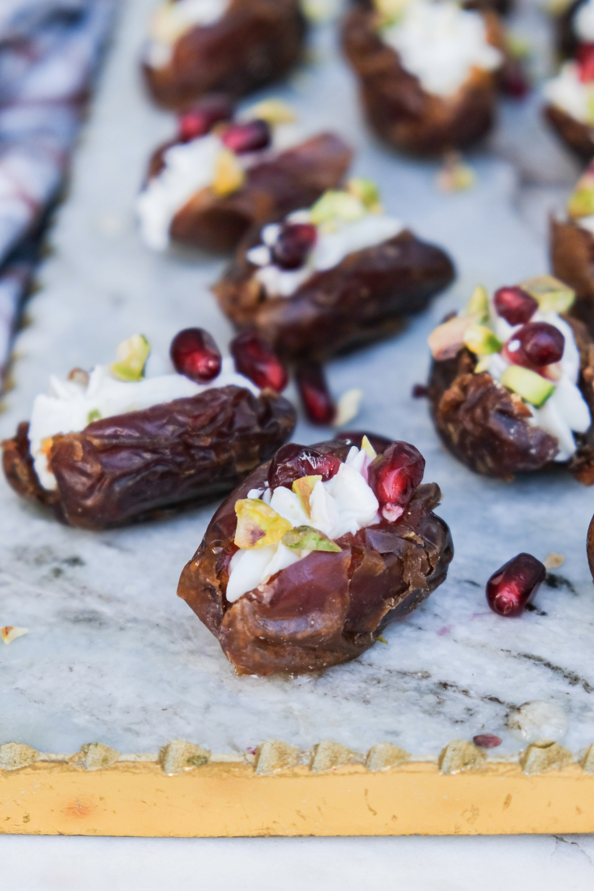 Sliced dates filled with goat cheese and topped with chopped nuts and pomegranate seeds.