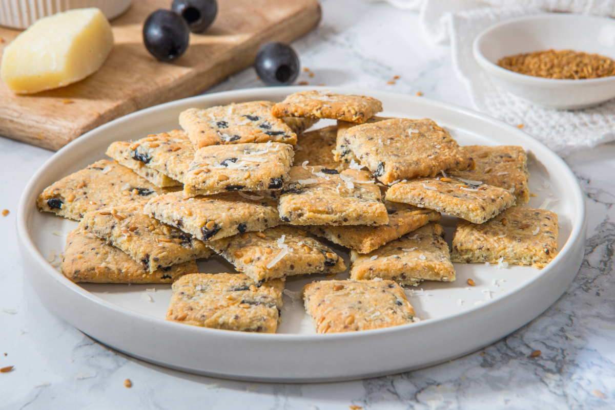 Small square homemade low carb crackers on a white plate with a rim.
