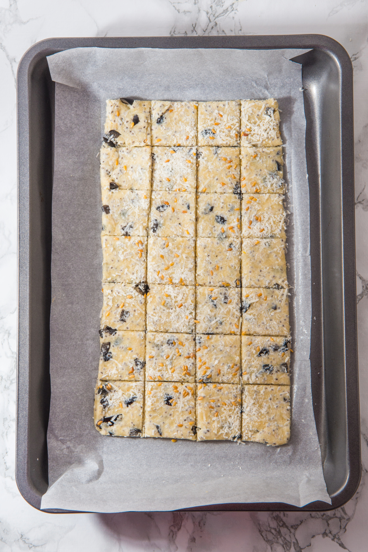 Cracker dough rolled flat and cut into squares placed on a baking sheet.