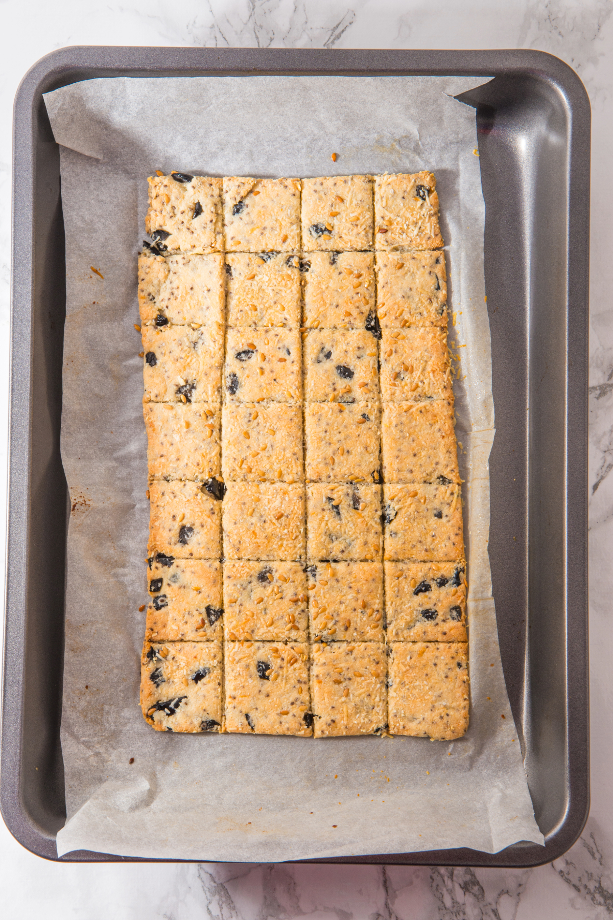Baked homemade crackers on a baking sheet.
