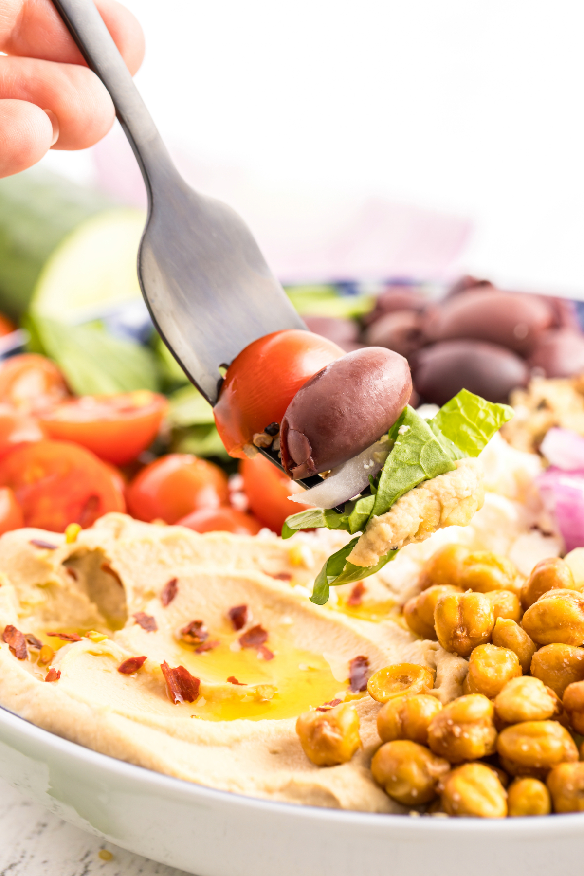 A fork full of salad with hummus.