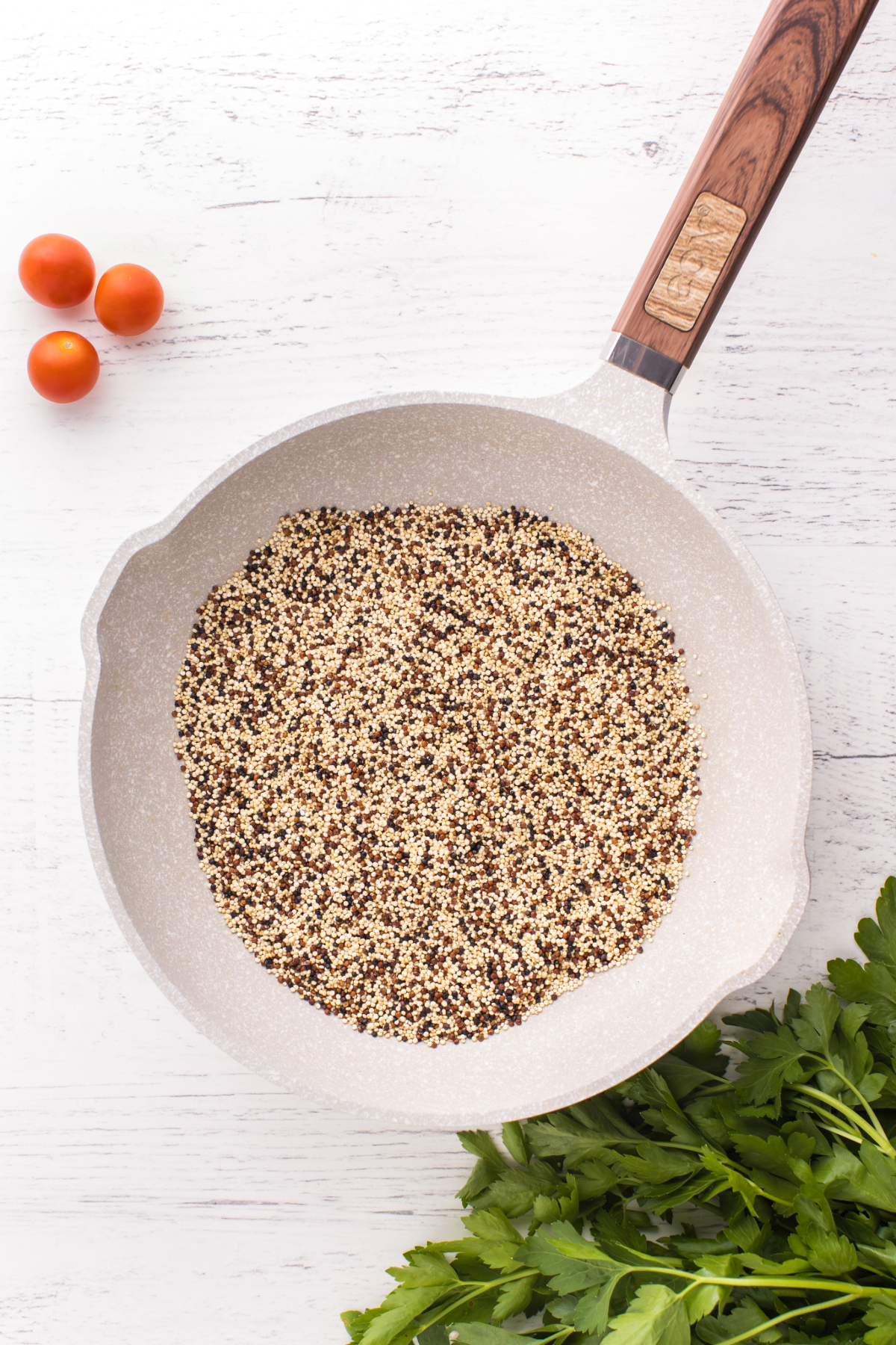 Toasting quinoa in a white skillet before cooking.