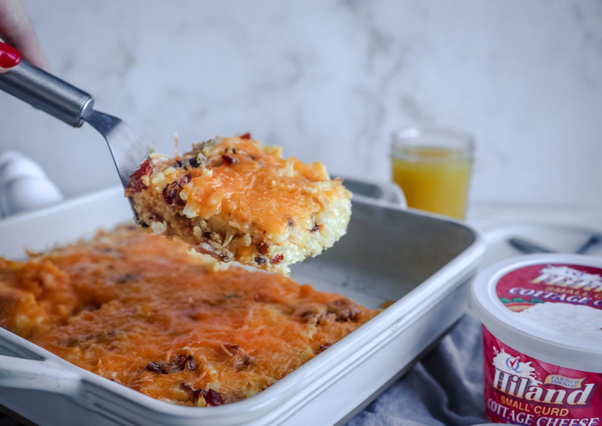 Slice of cottage cheese breakfast casserole held on a spatula.