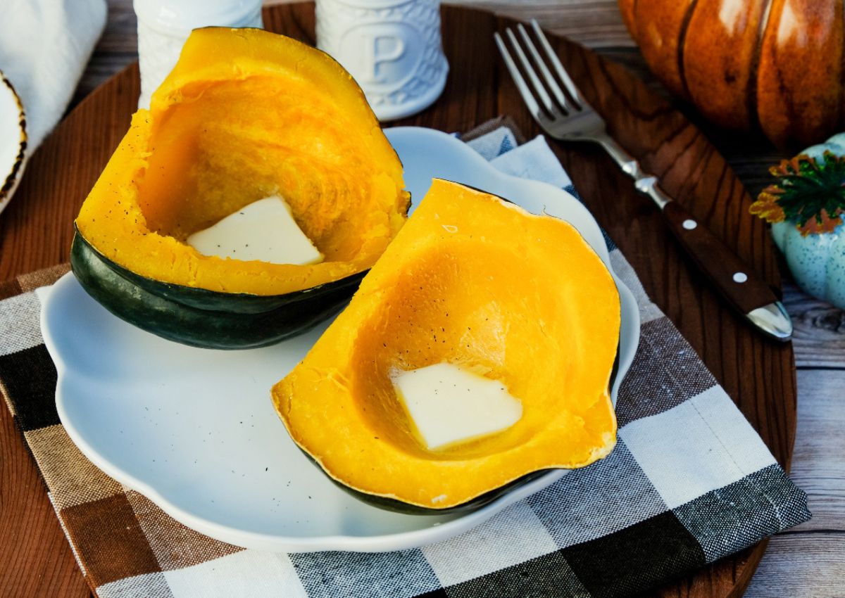 Acorn squash cut in half on a plate with butter inside.