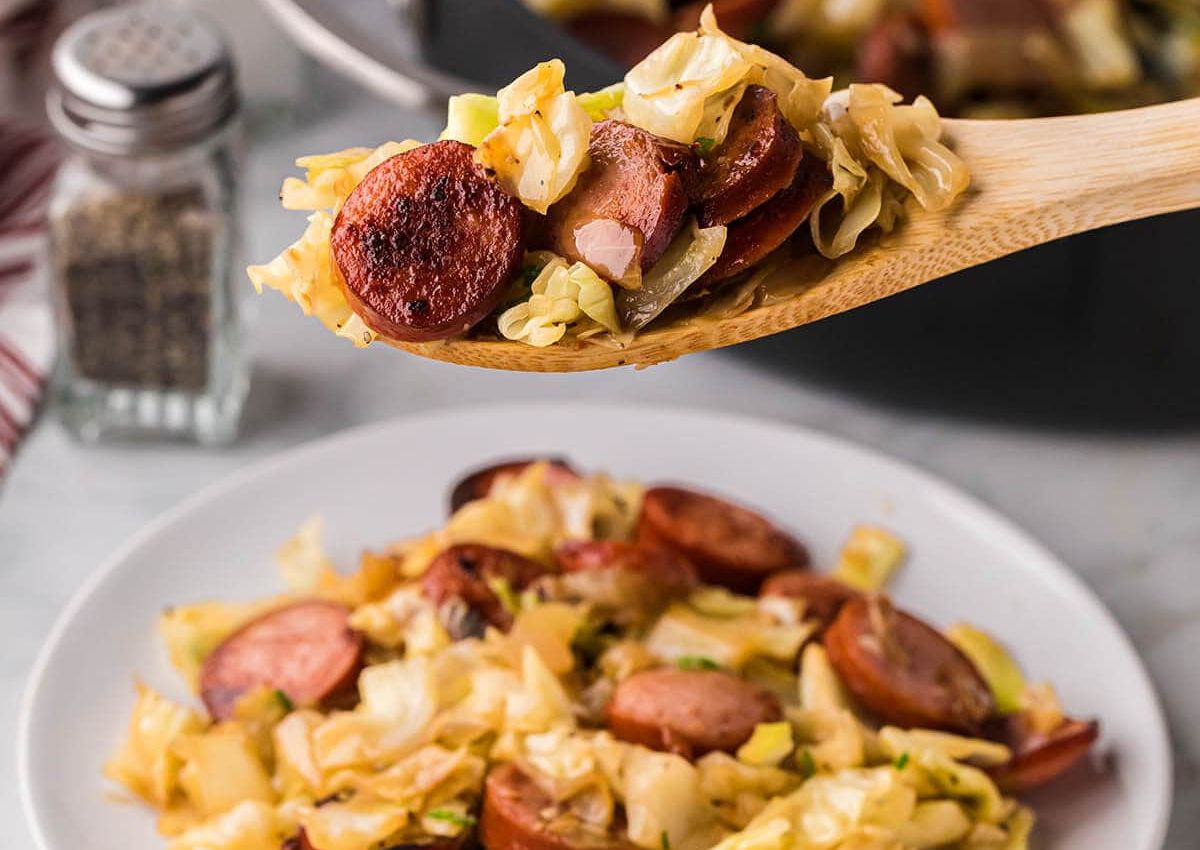 Wooden spoonful of kielbasa and cabbage.