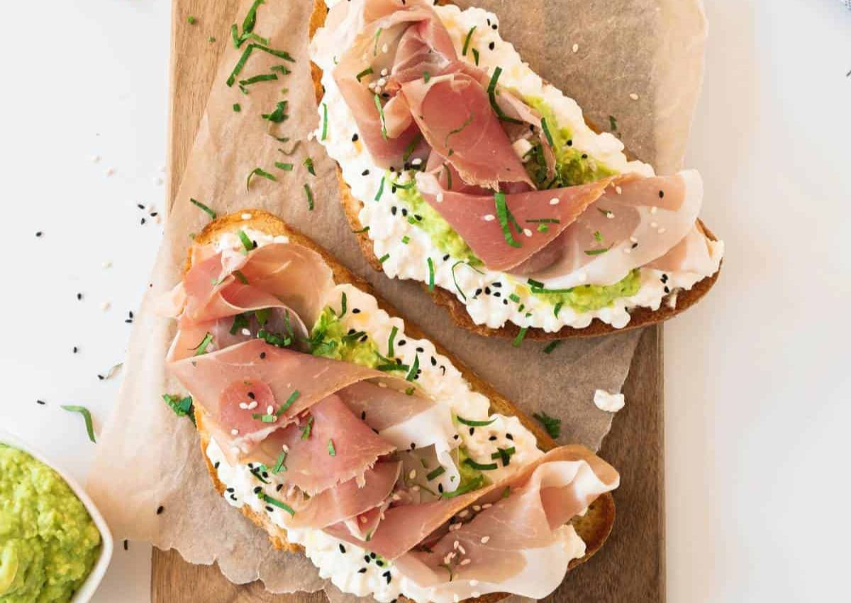 Open faced prosicutto sandwich on table.