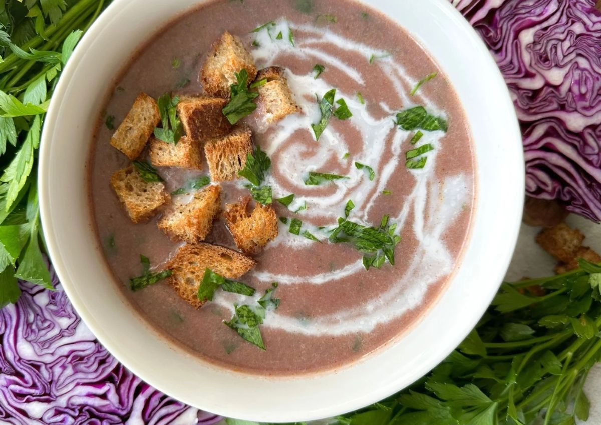 Bowl of red cabbage soup with croutons.