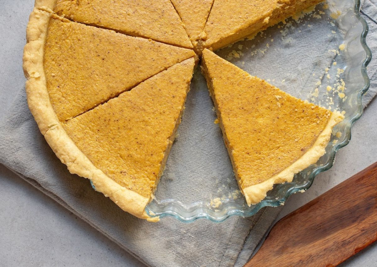 Winter squash pie in a glass pie dish with two slices missing.