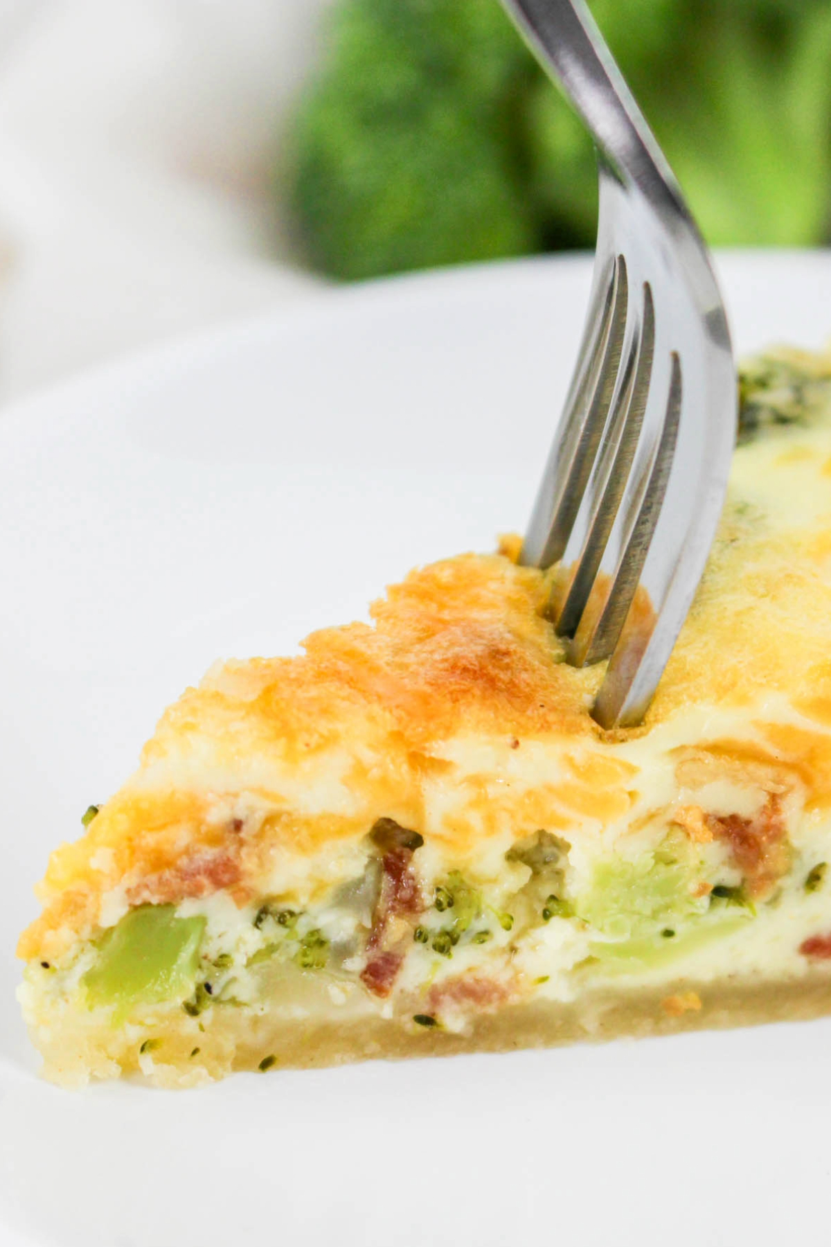 A fork in the middle of a slice of quiche ready to eat.