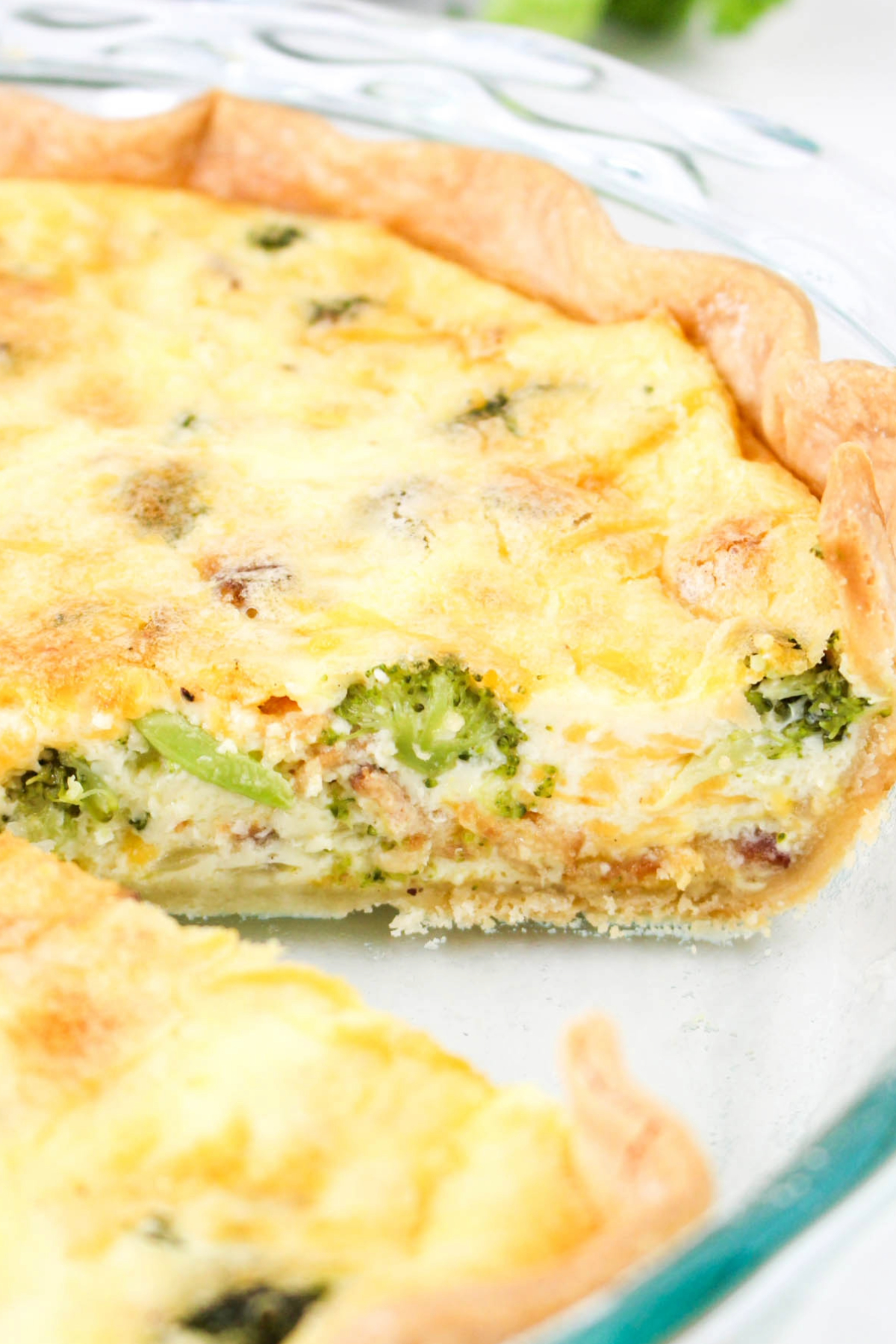 Homemade broccoli and bacon quiche in a glass pie plate.
