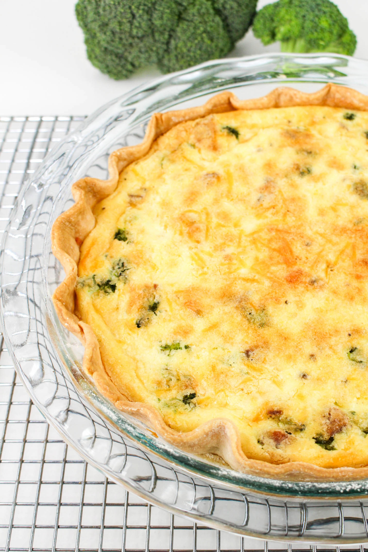 A whole cooked quiche on a silver cooling rack.