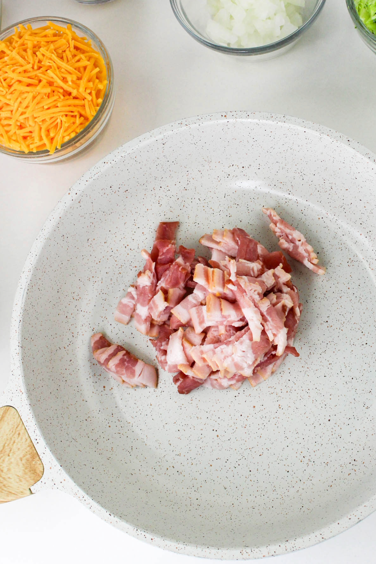 Diced bacon in a white skillet before cooking.