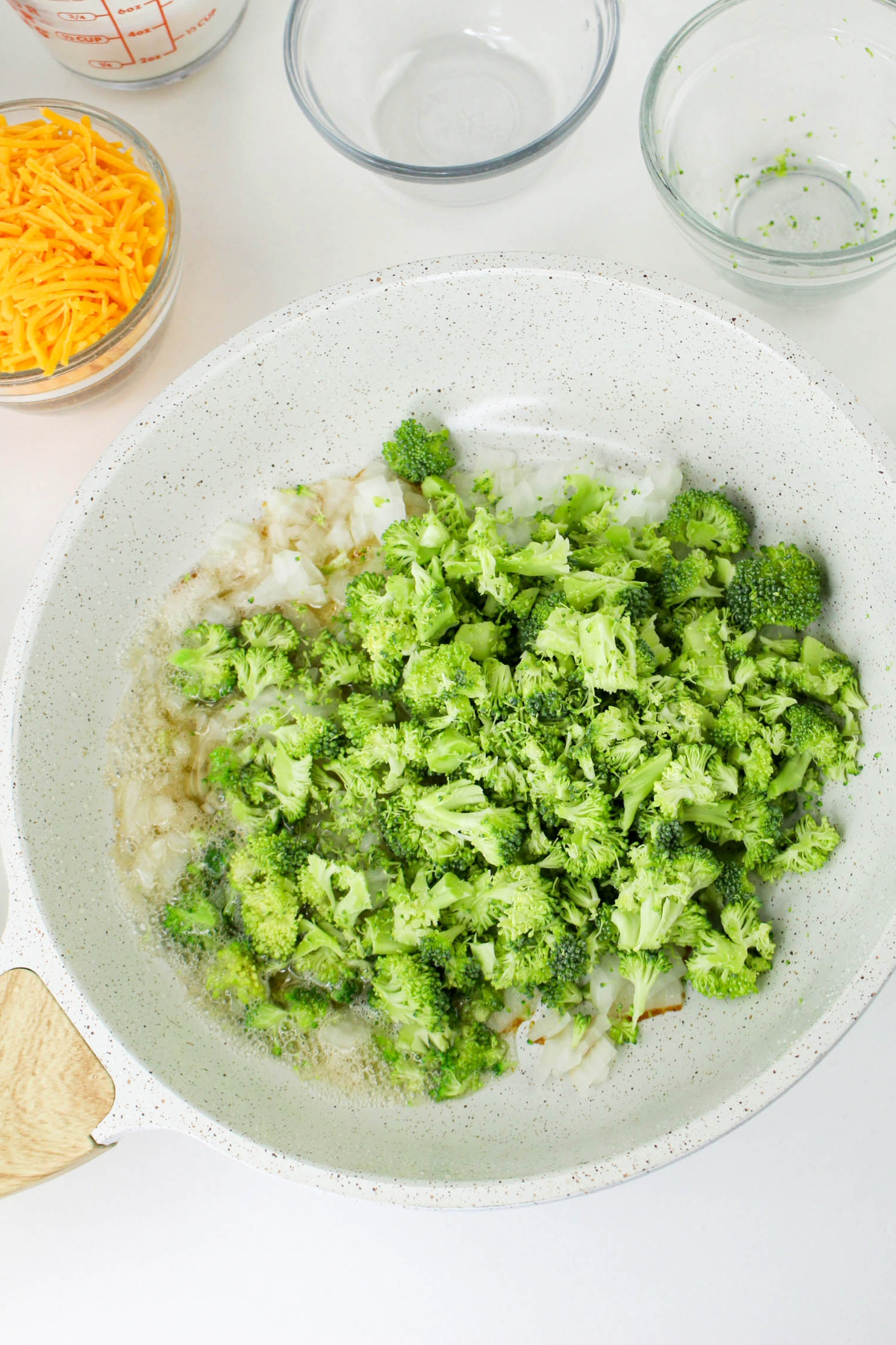 Sautéing diced onion and broccoli florets in a skillet.