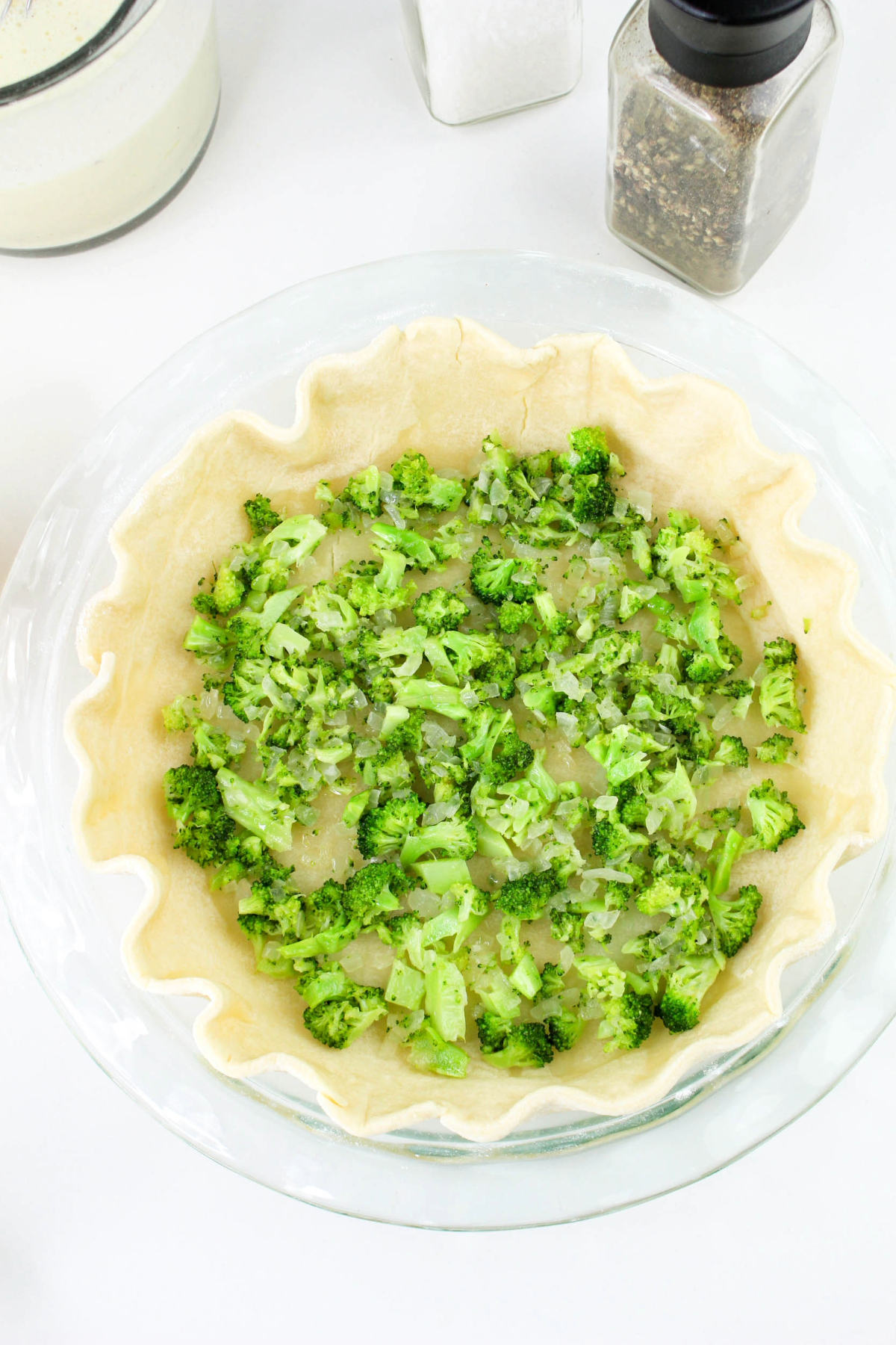 Sautéed broccoli and onion mix placed in a pie crust before adding the quiche filling.