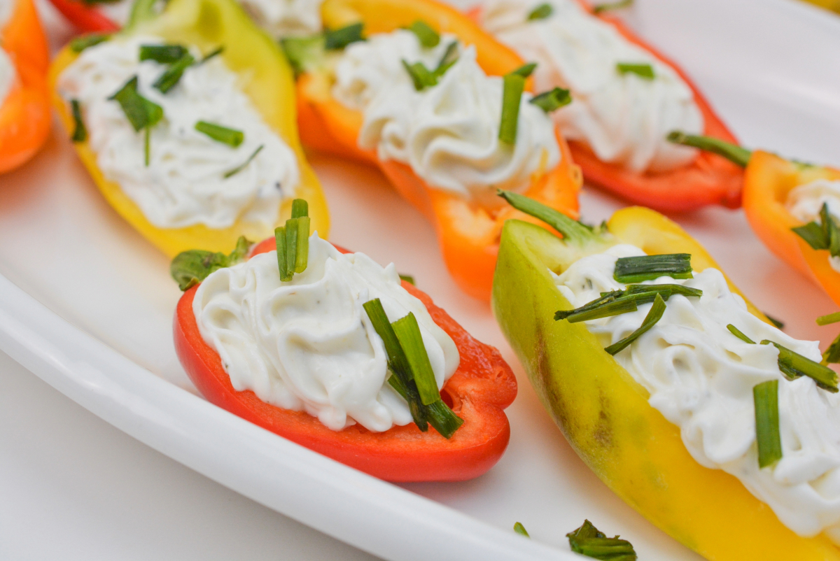 Sliced yellow and red mini peppers filled with goat cheese.