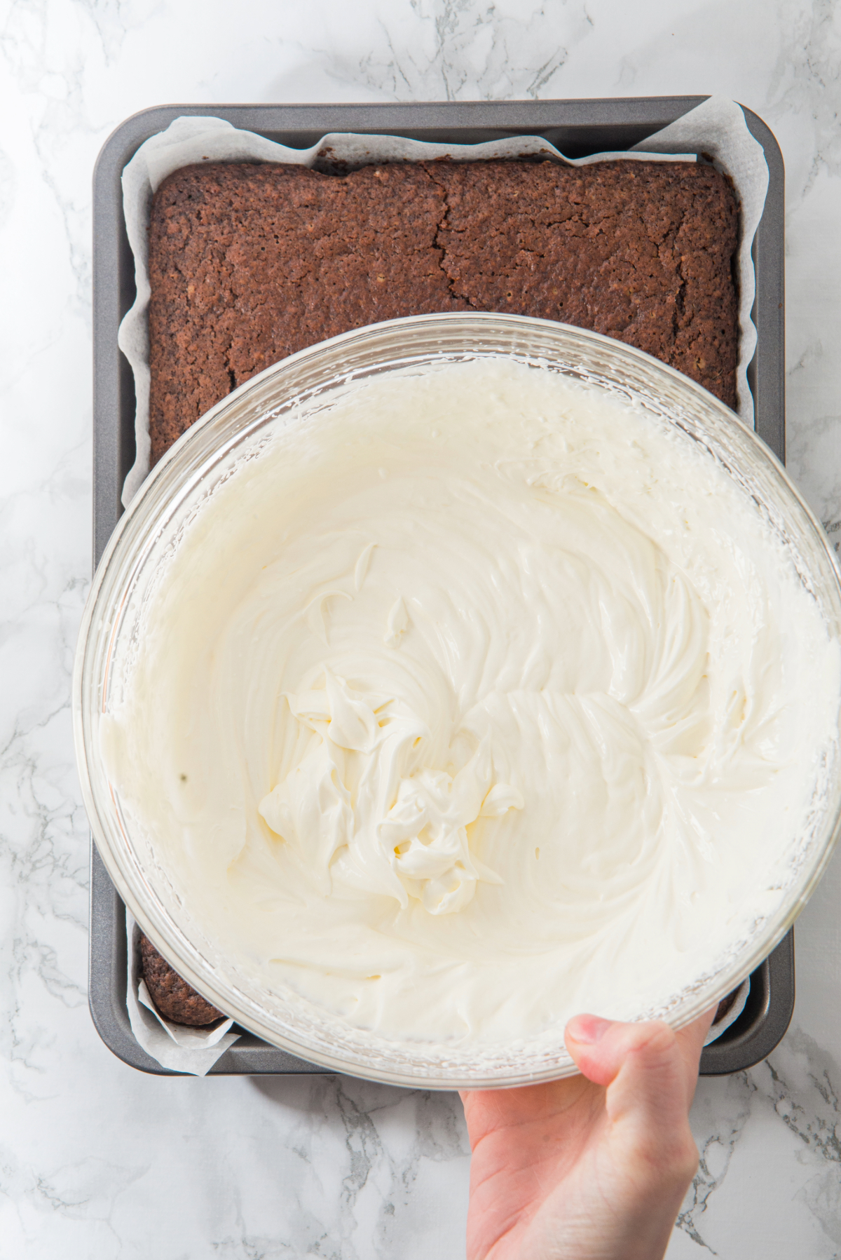 Cream cheese frosting mixed in a clear bowl before adding to the chocolate cake.