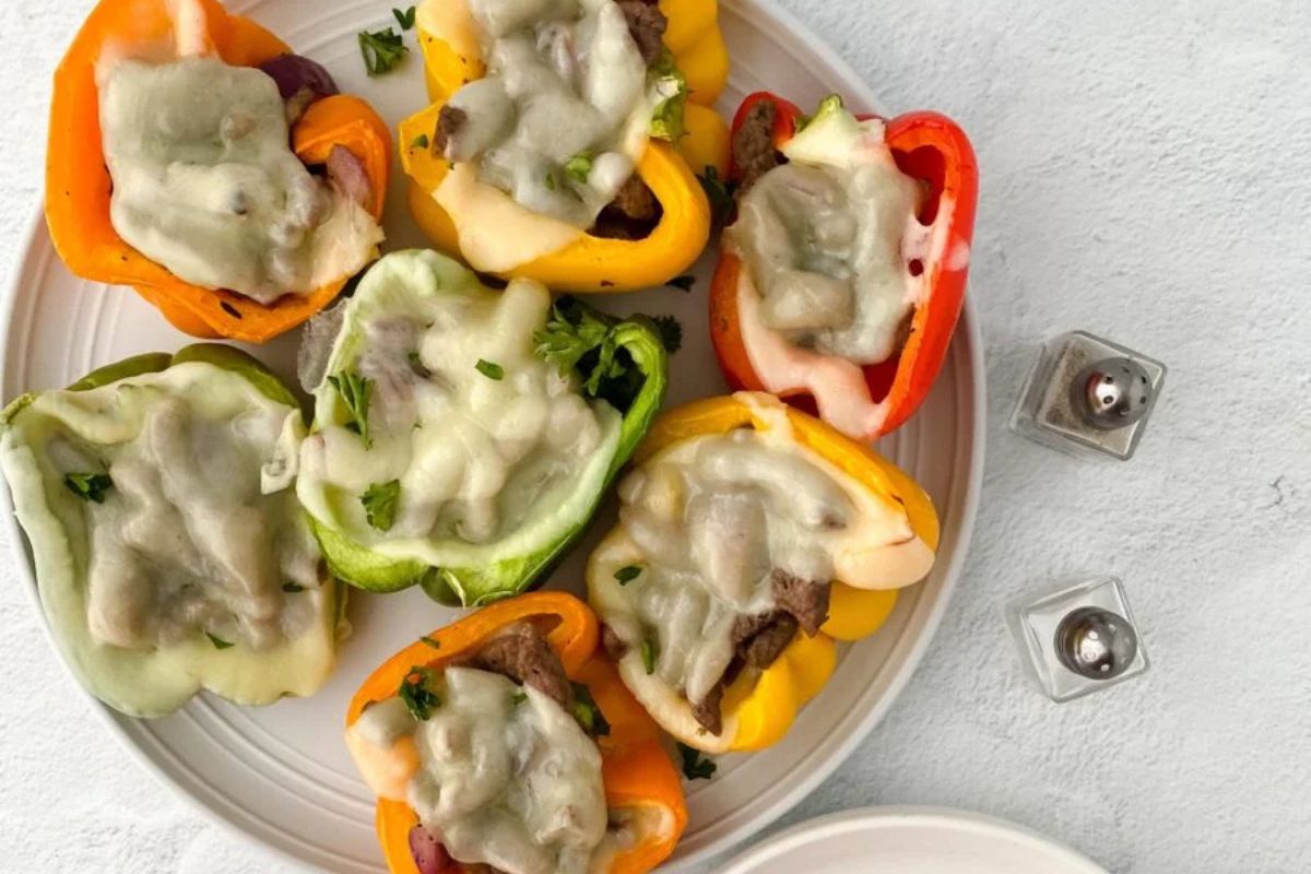 A plate of baked bell pepper halves filled with melted cheese and garnished with herbs.