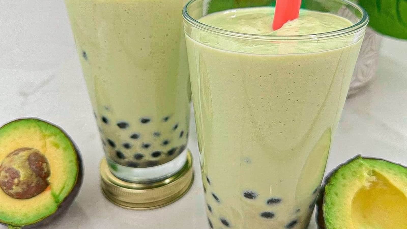Creamy avocado smoothie with chewy boba pearls in glasses with a pink color straw.
