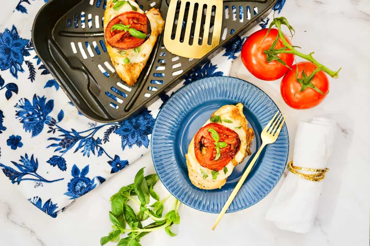 Chicken caprese on a blue plate.