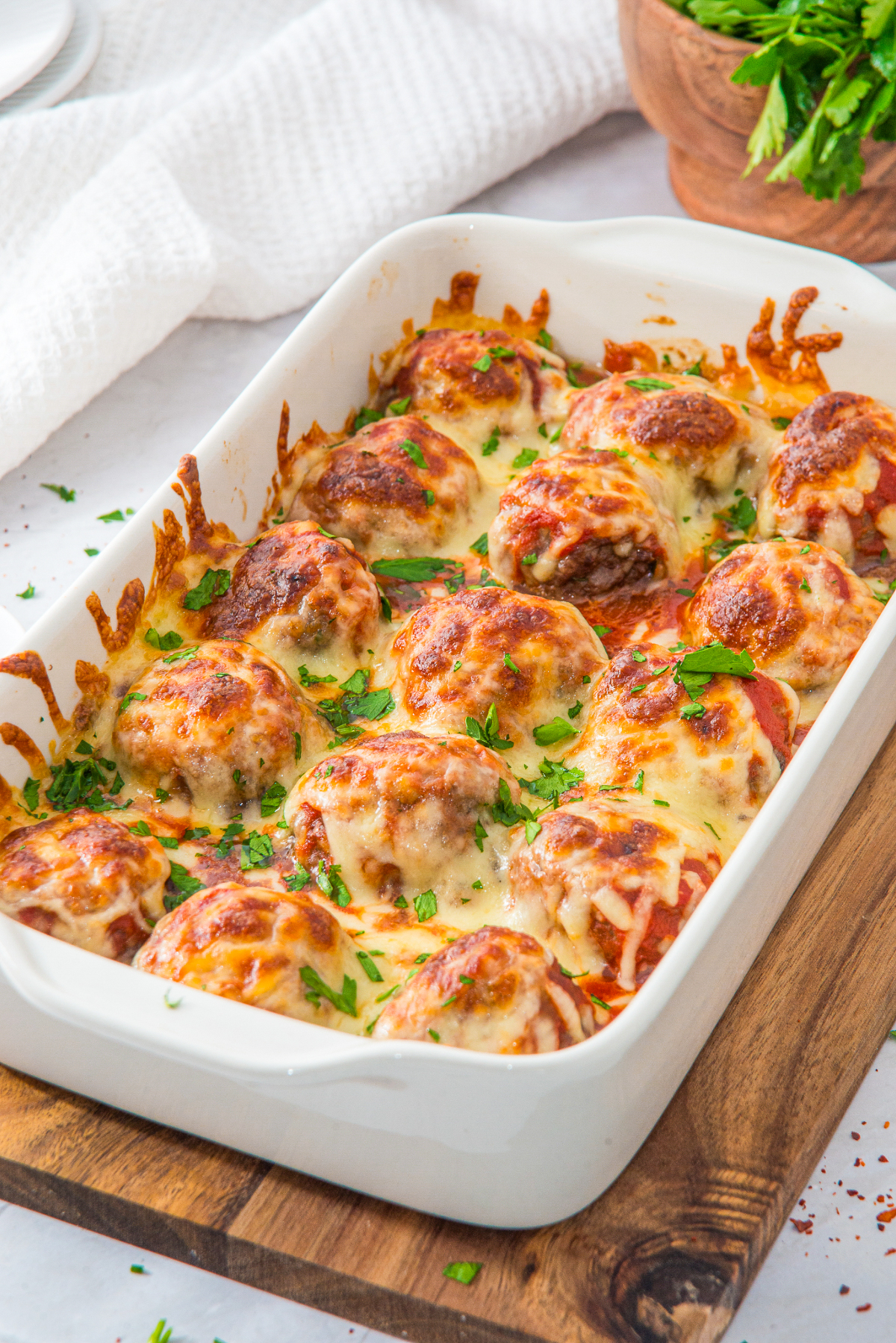 Baked meatballs topped with melted cheese in a white serving dish.