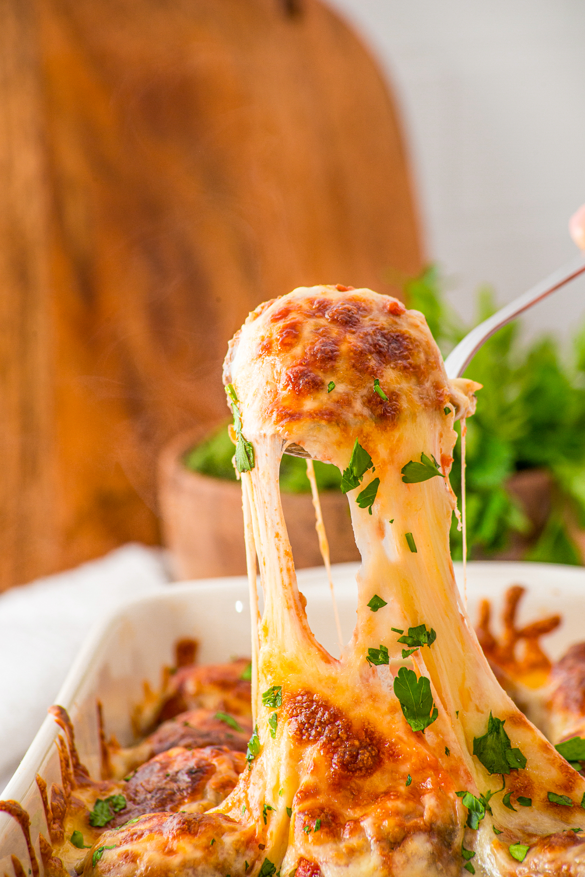 Gooey cheese surrounding a meatball when scooped up with a spoon.