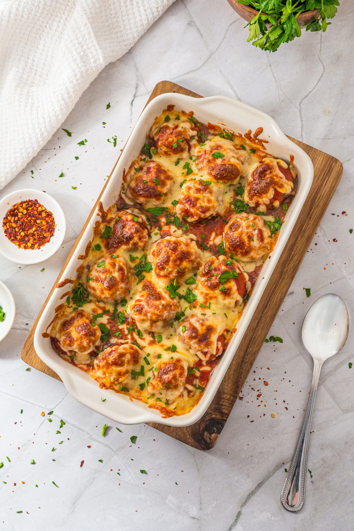 Overhead view of baked meatballs topped with melted cheese before serving.