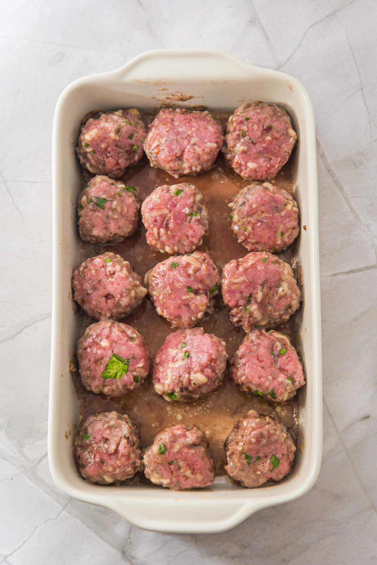 Formed meatballs in a baking dish cooked partially.