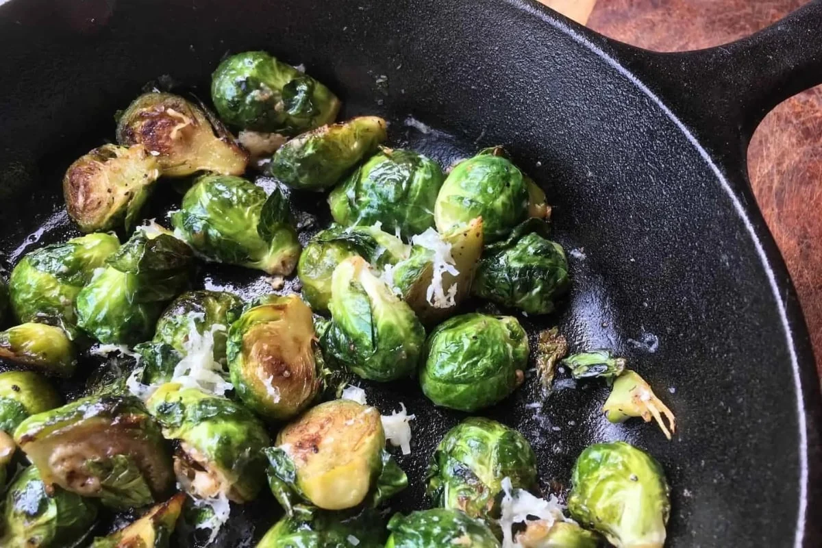 Cast iron skillet full of roasted brussels sprouts with balsamic glaze. 