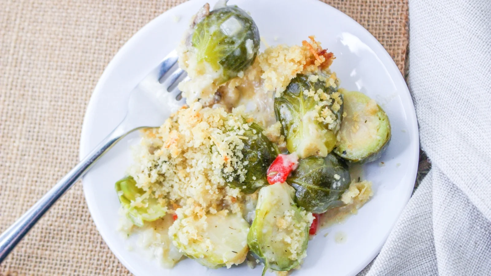 Small white plate full of cheesy brussel sprouts.