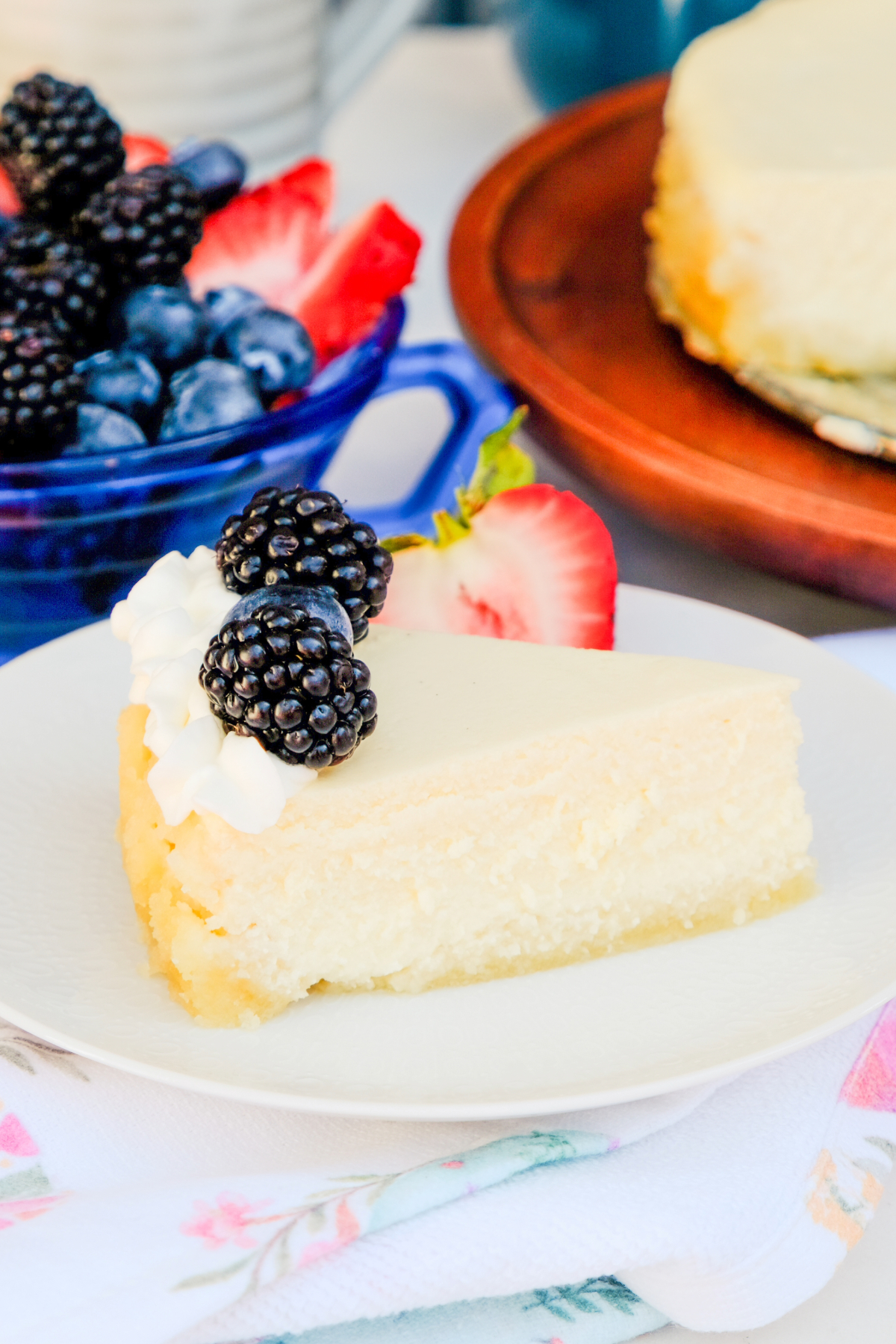 A slice of cottage cheese cheesecake on a white plate topped with fresh berries.