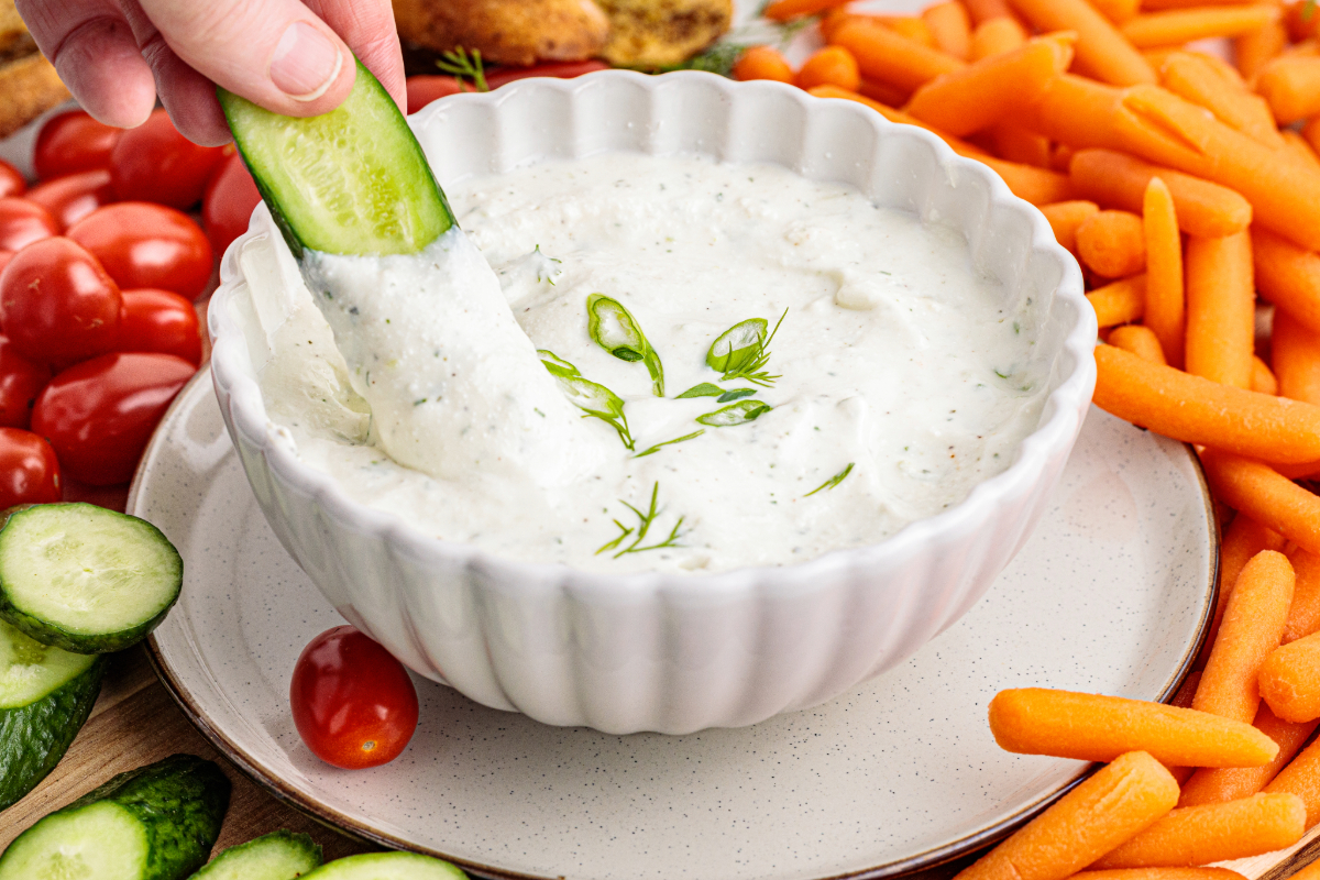 Ranch dip in a white bowl with a fresh carrot scooped in the dip.