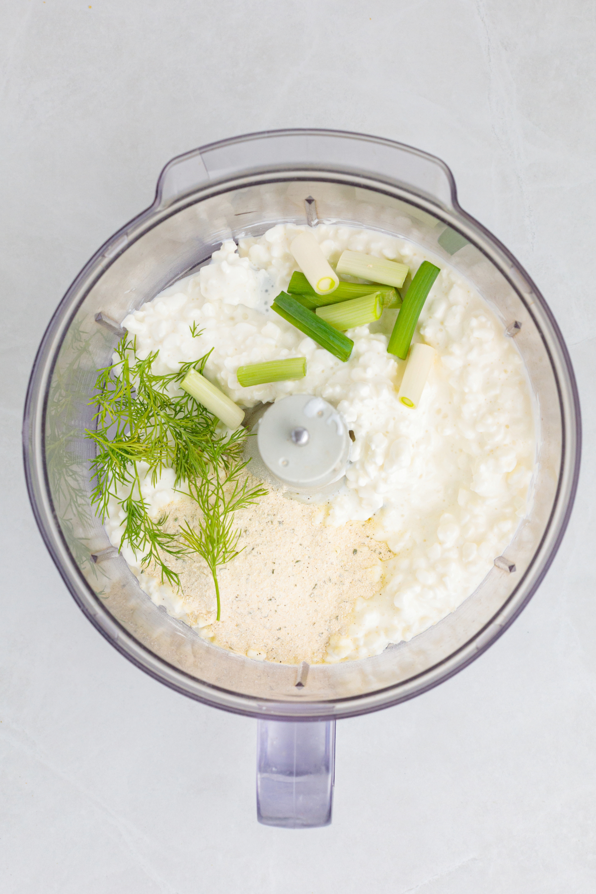 Ingredients in a food processor for cottage cheese ranch dip before blending.