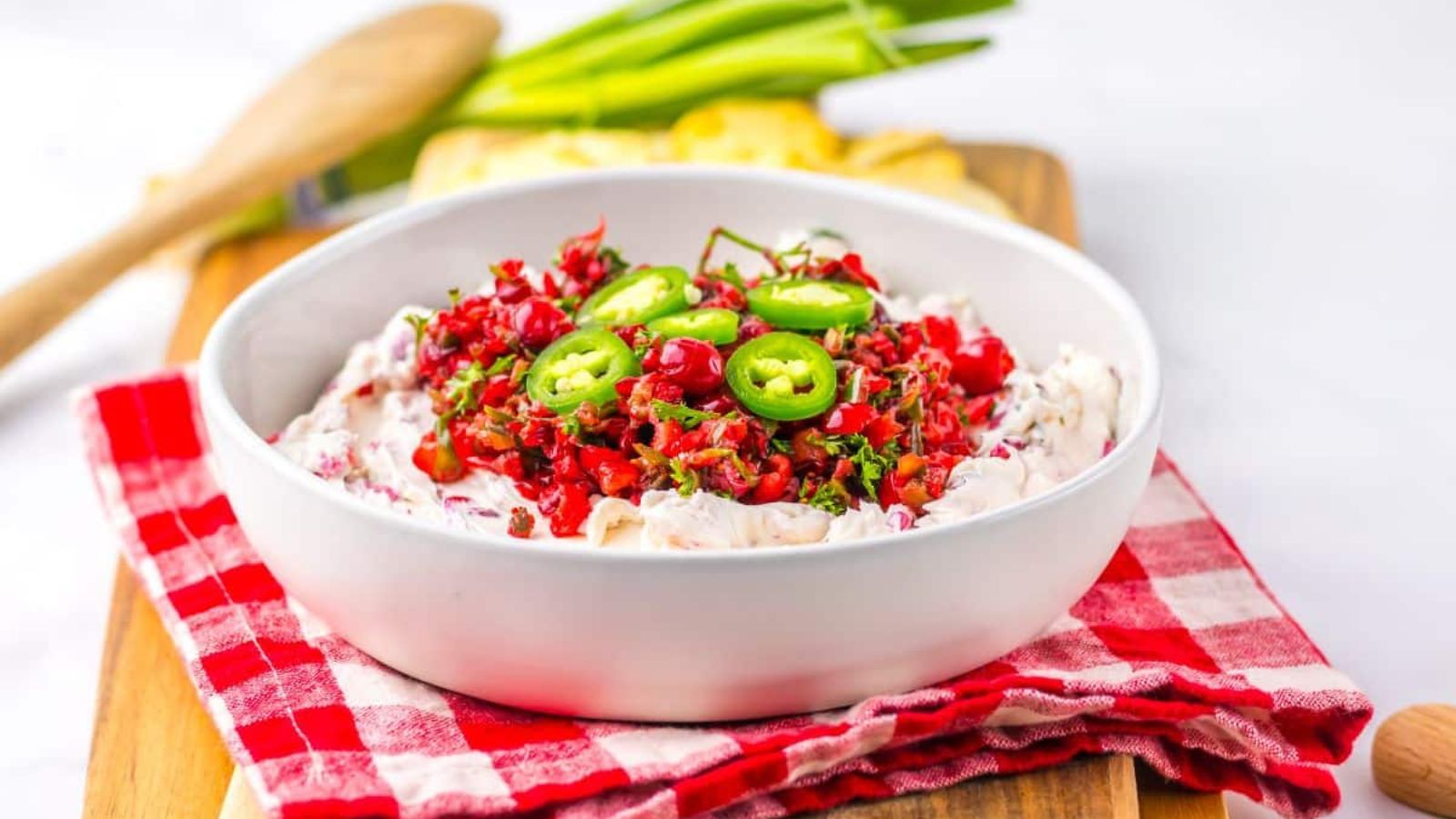 Bowl full of cranberry jalapeno dip on a wooden cutting board.