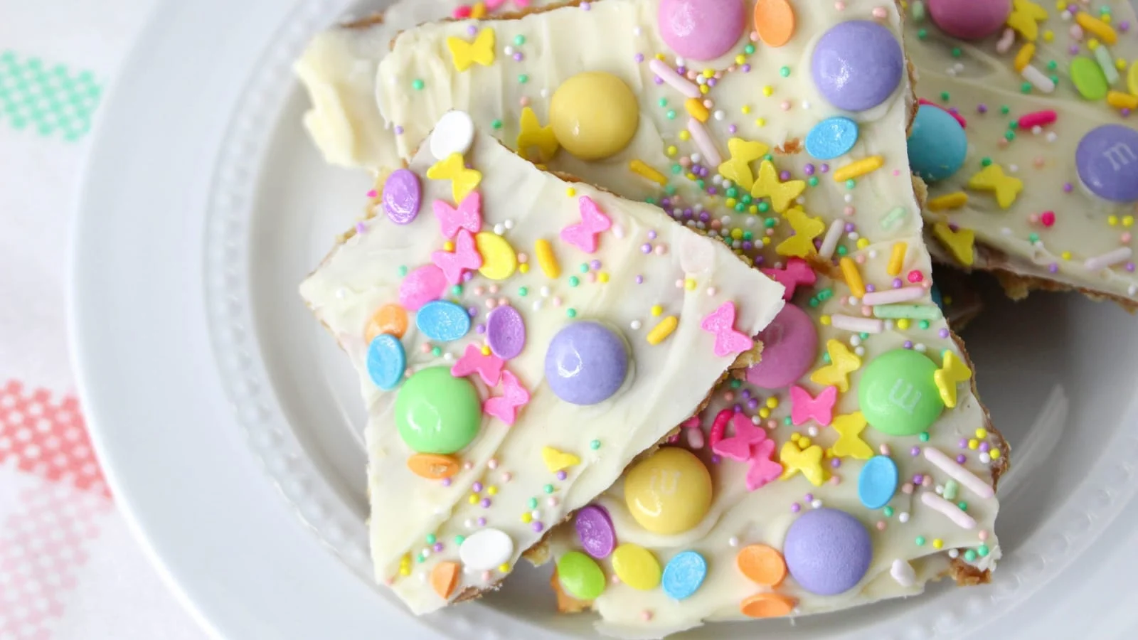 Pieces of candy bark topped with M&M's and sprinkles on a plate.