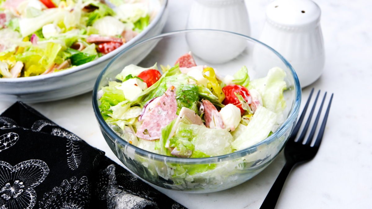 Grinder salad in a clear bowl with a fork on the side ready to eat.