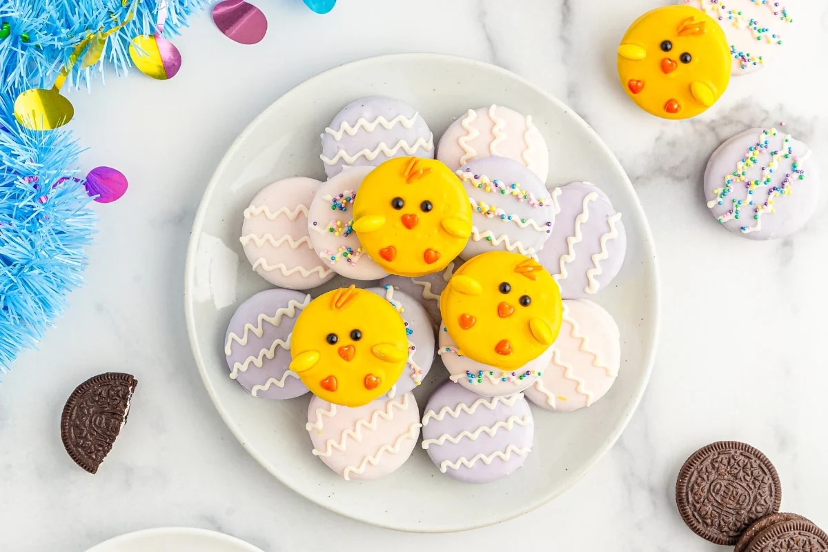 Plate full of chocolate covered oreos decorated like chicks and eggs.