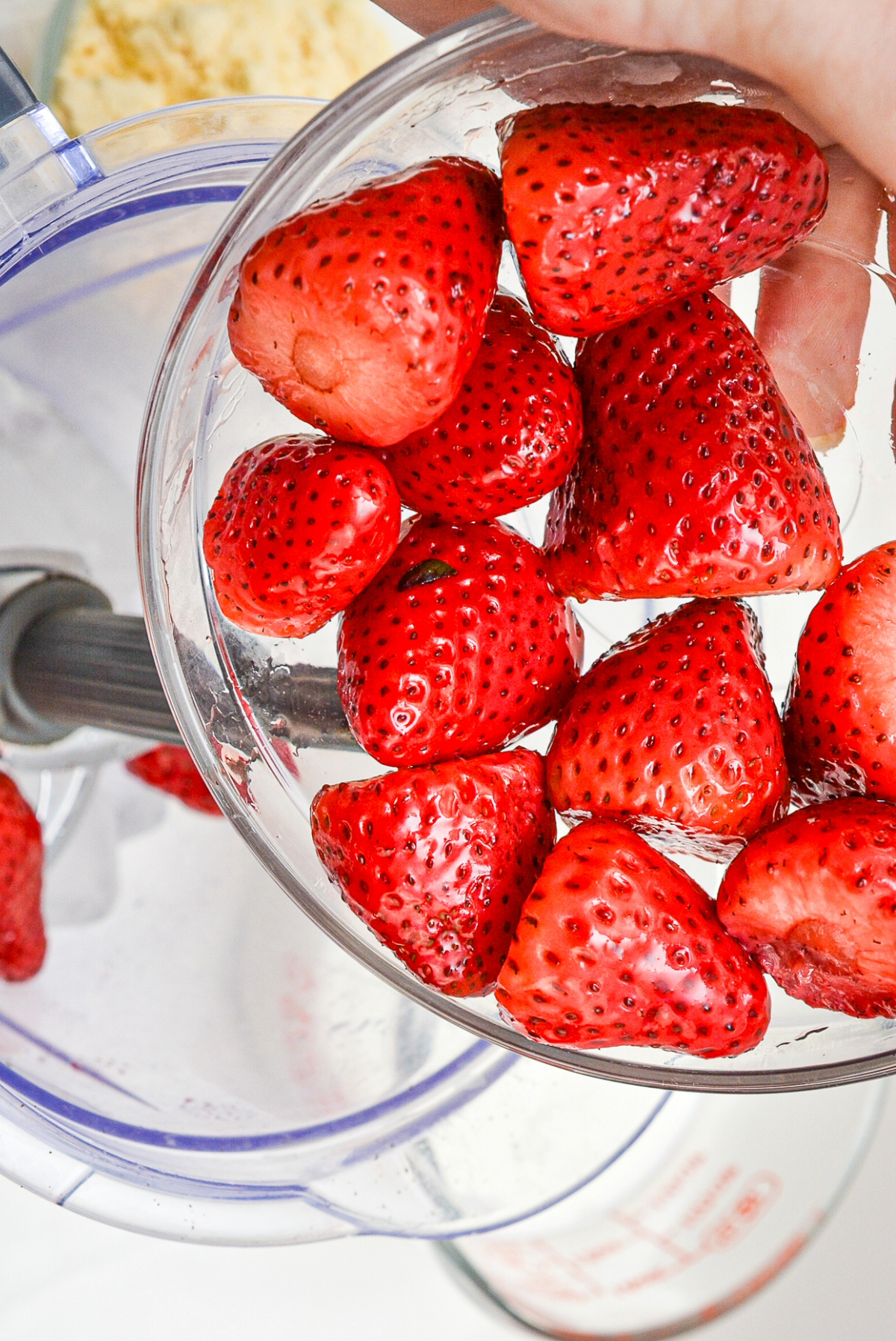 Fresh strawberries in a clear bowl before adding to a blender.