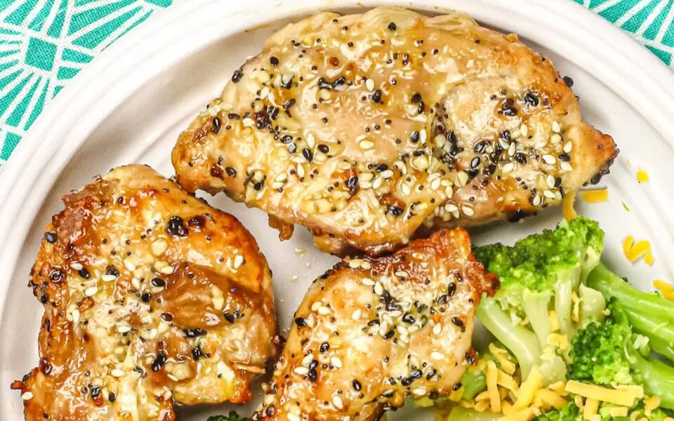 Boneless chicken thighs on a white plate topped with everything bagel seasoning.