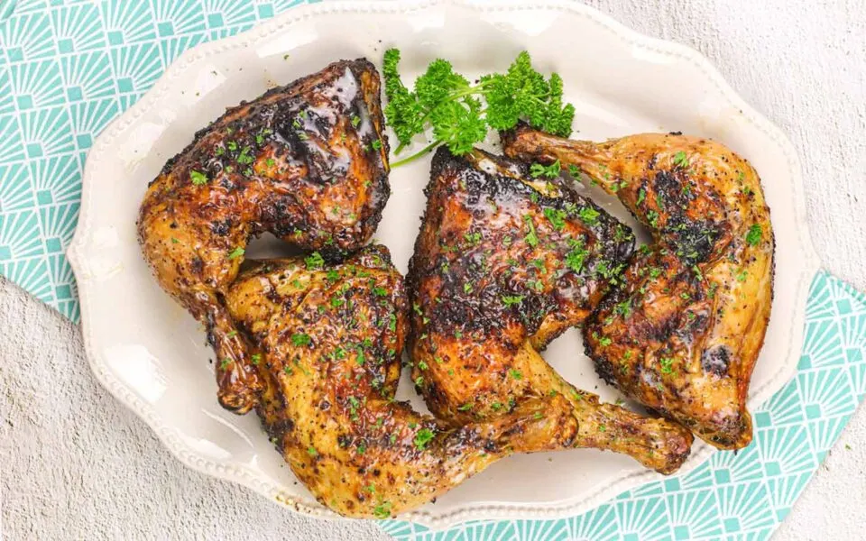 Air fryer chicken leg quarters on a platter with parsley.