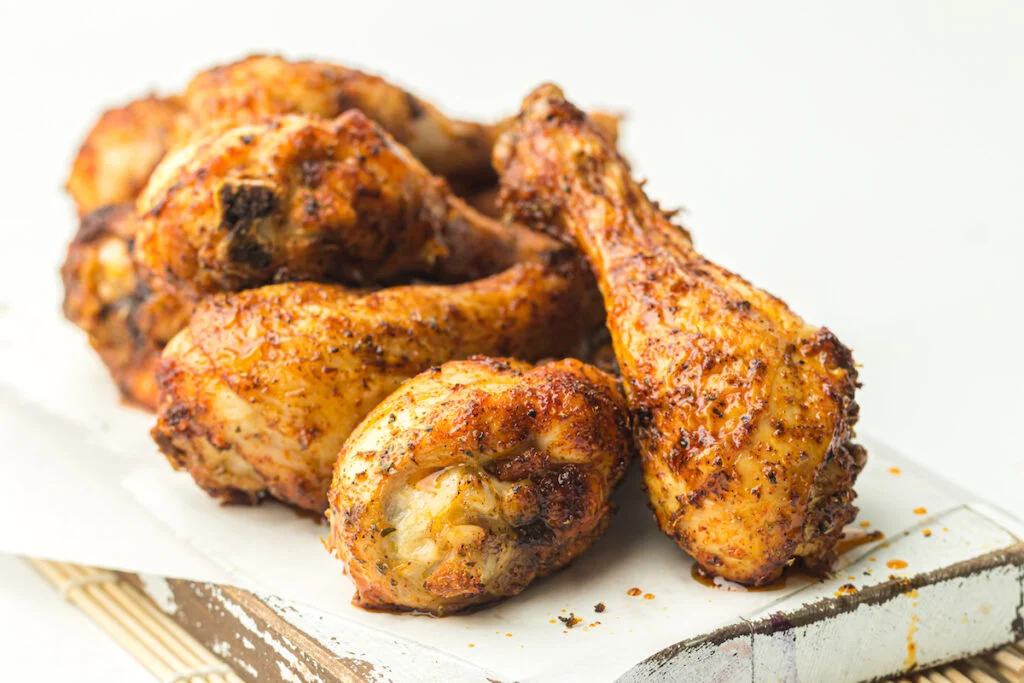 Chicken drumsticks on a wooden cutting board.