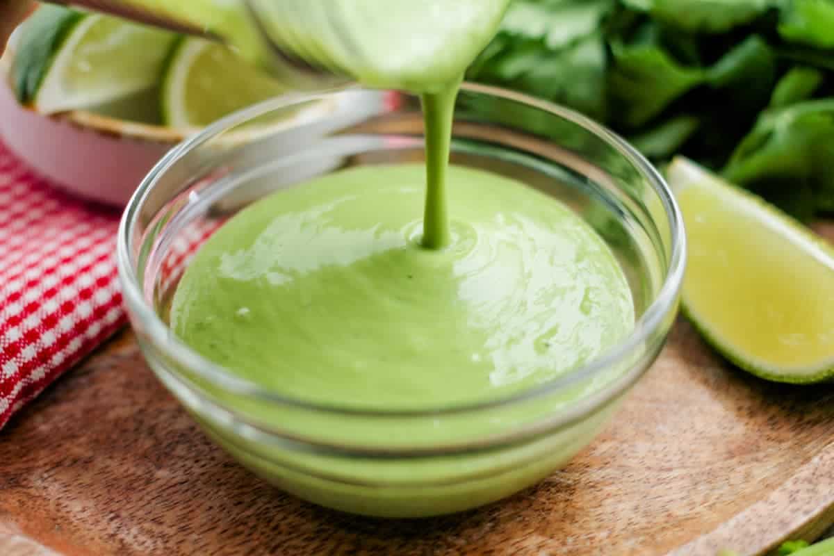 Avocado cilantro dressing being poured into a small dish.