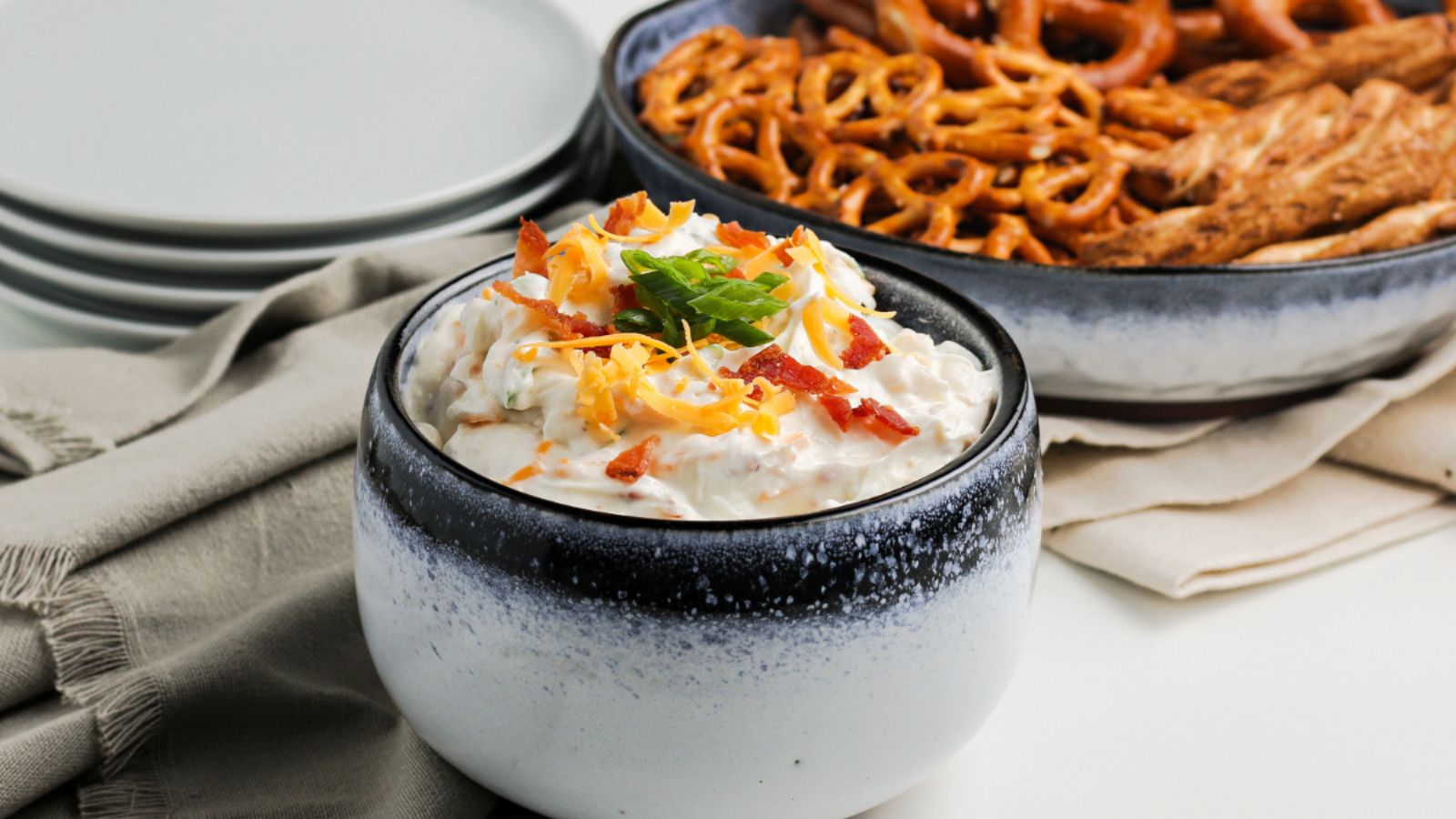 Bowl full of Bacon Cheddar Dip that is garnished with cheese and cooked bacon.