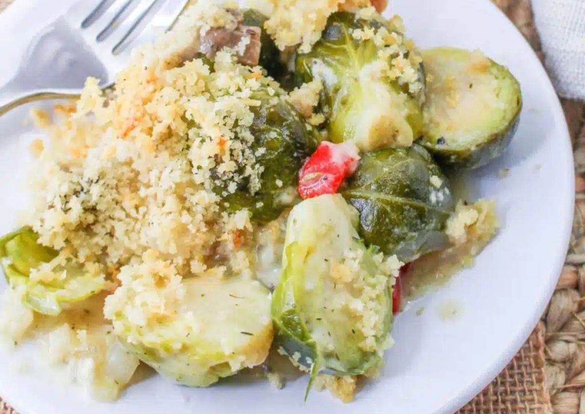 Serving of cheesy brussel sprouts casserole on a plate with a fork. 