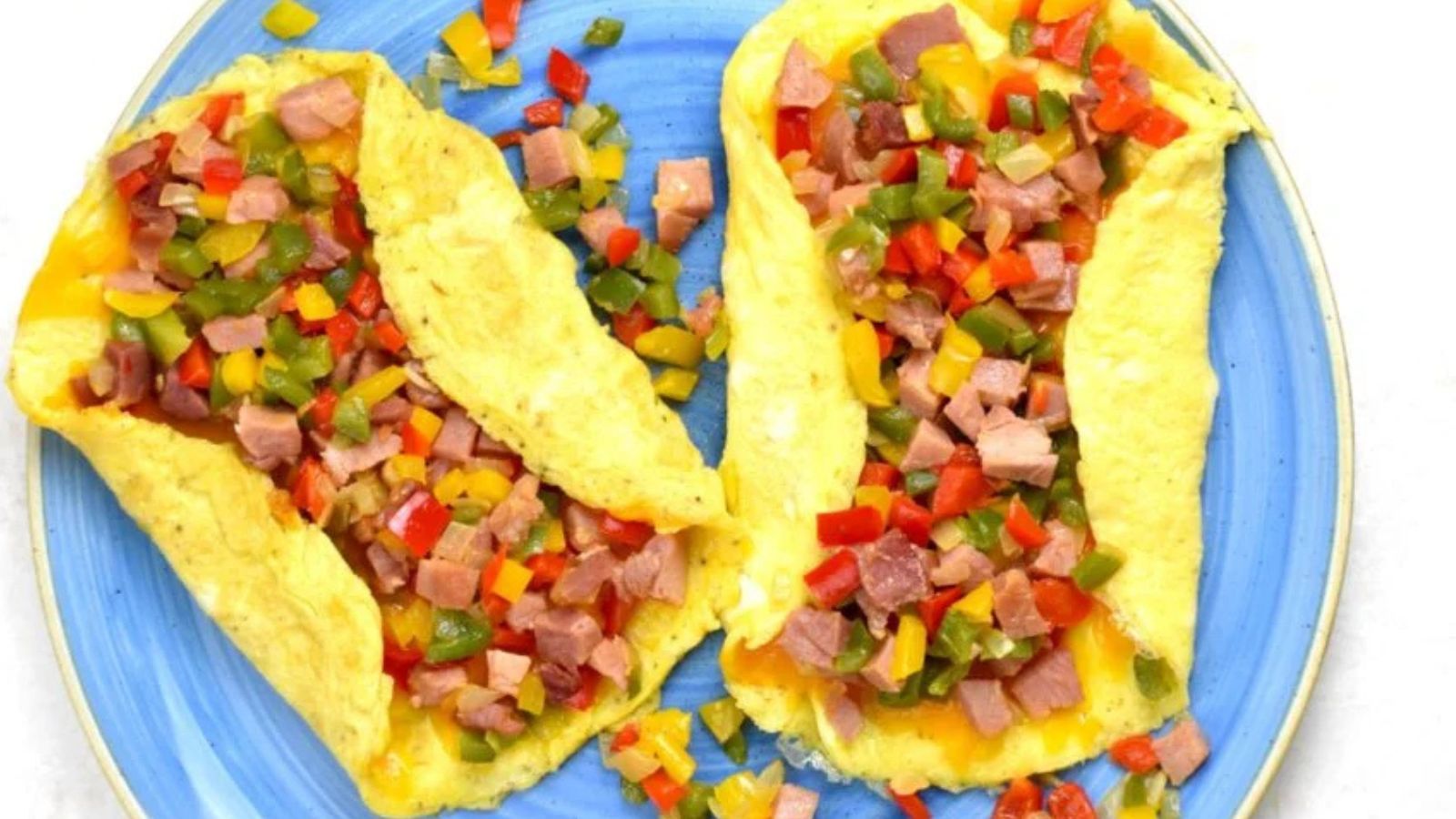 Two denver omelettes on a blue plate. 