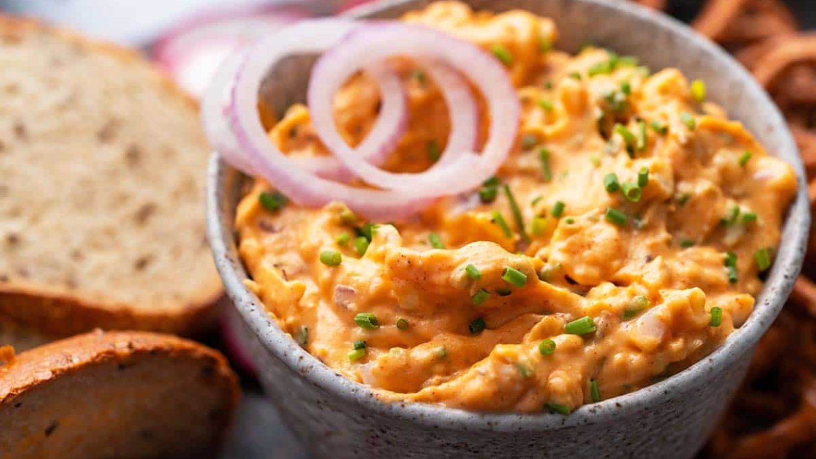 Bowl full of german beer cheese dip and topped with raw red onion.