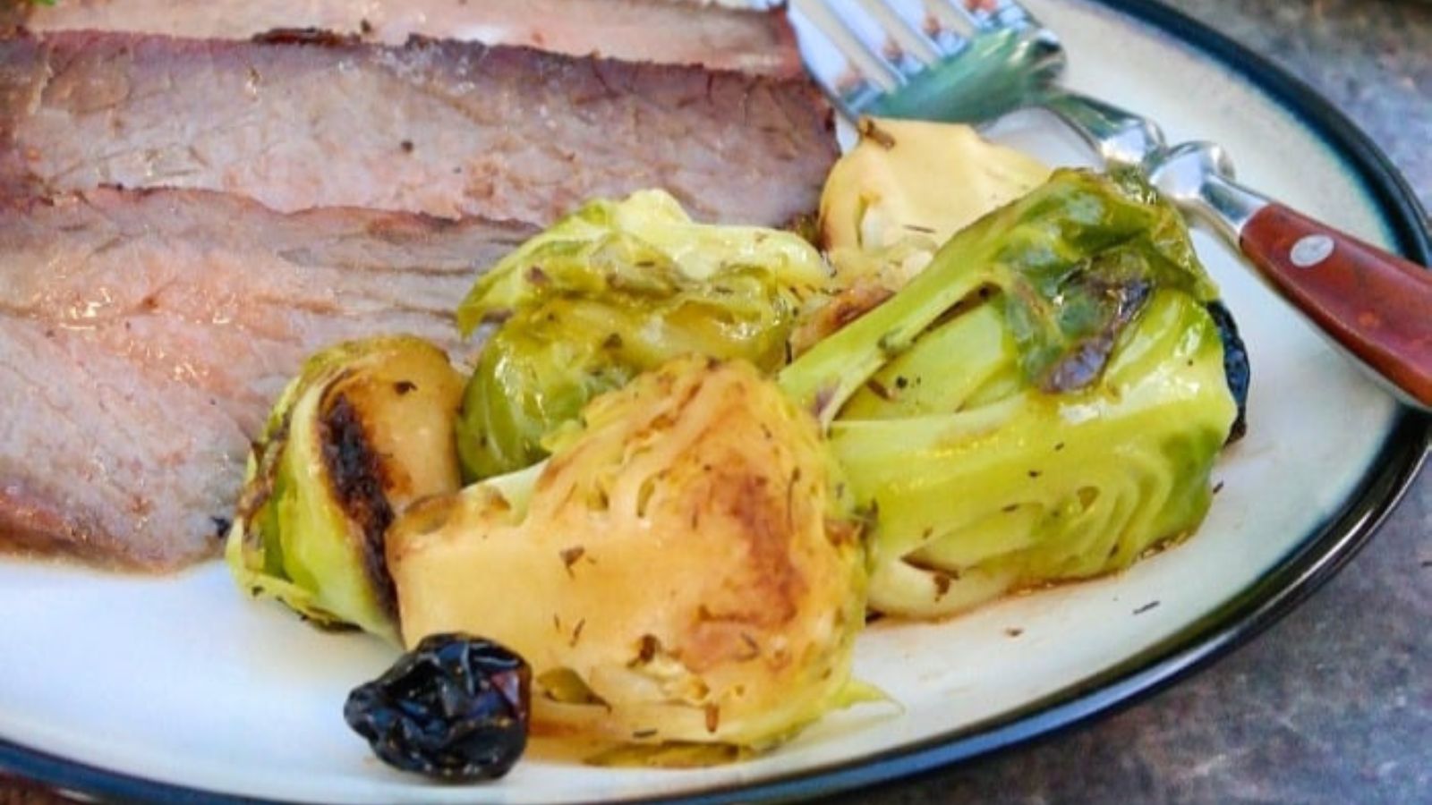 Maple glazed brussels sprouts on a plate with slices of beef. 