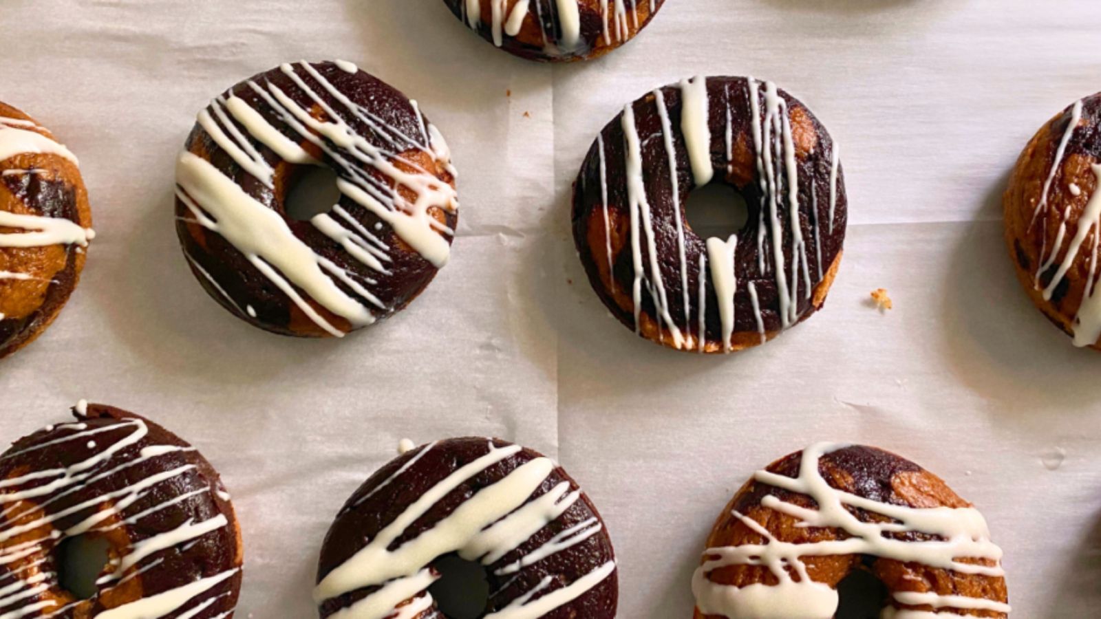 Marbled protein donuts on a parchment lined baking sheet. 