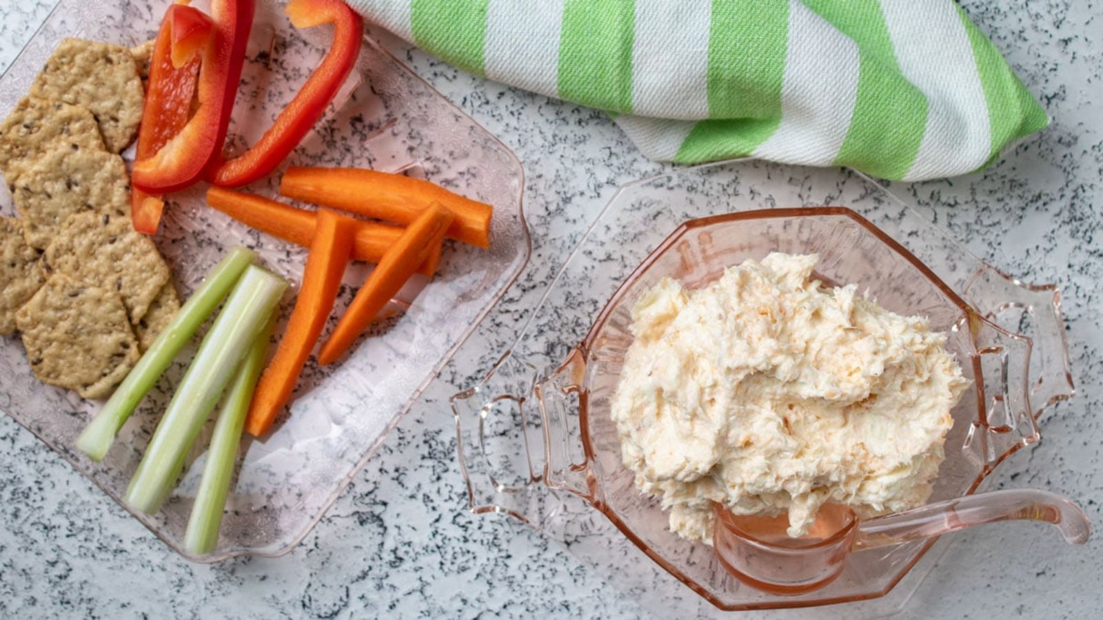 Bowl fo shrimp dip with a plate of veggie sticks and crackers.